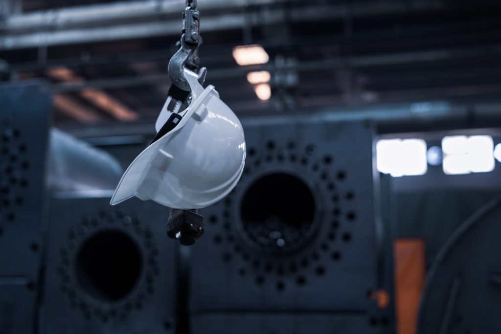 g- A hard hat hanging from a chain in a factory.